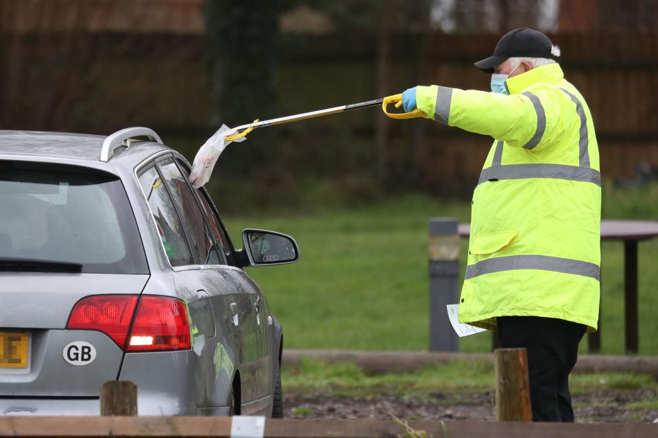 A test and trace worker in the Bramley Inn car park in Bramley, near Basingstoke, Hampshire takes a coronavirus test from a driver at a surge testing programme with local residents, after a case of the South African variant of Covid-19 was identified in the village (PA)