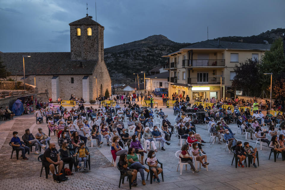 Spectators wearing face masks and keeping social distance to protect against the coronavirus attend a variety show in the village of Bustarviejo, outskirts of Madrid, Spain, Monday, Sept. 14, 2020. (AP Photo/Bernat Armangue)