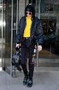 <p>In a black bomber jacket, hoodie, yellow zip-up top, beanie, sunglasses, embroidered dark jeans, patent buckled boots and a leather satchel while out in NYC.</p>