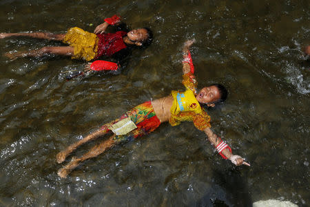 Children lie in water as sea water rises during high tide at Kali Adem port in Jakarta, Indonesia, January 3, 2018. REUTERS/Beawiharta