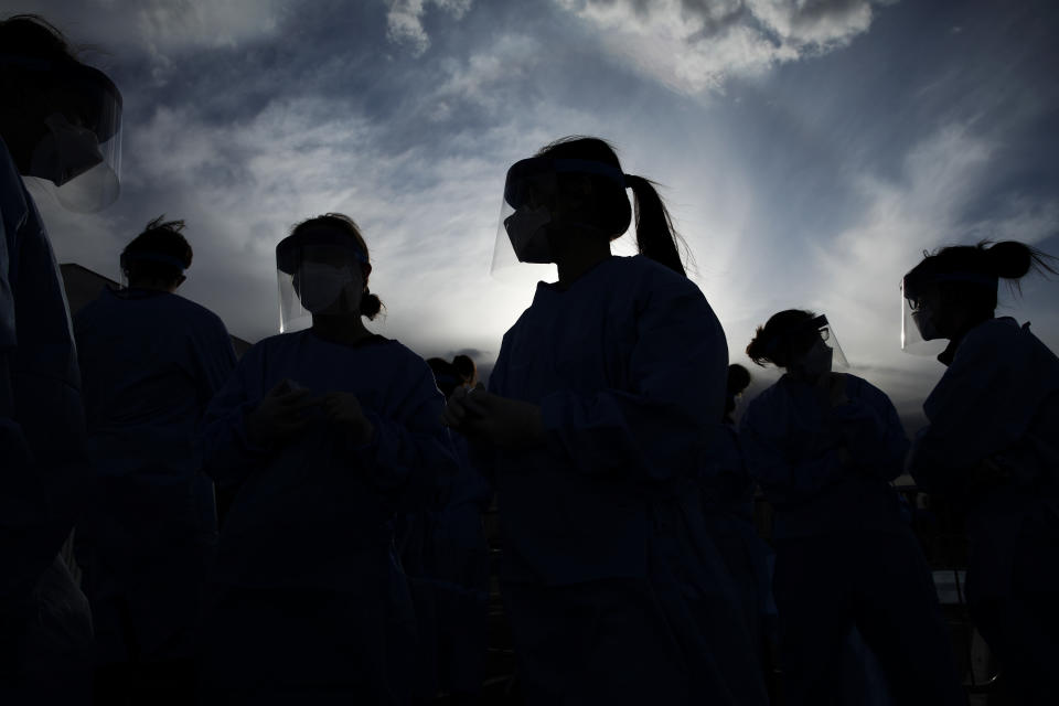 Medical and physician assistant students wear personal protective equipment as they prepare to screen for possible coronavirus cases at a makeshift camp for the homeless, March 28, 2020, in Las Vegas. Officials opened part of a city parking lot as a makeshift homeless shelter after a local shelter closed when a man staying there tested positive for coronavirus. (AP Photo/John Locher)