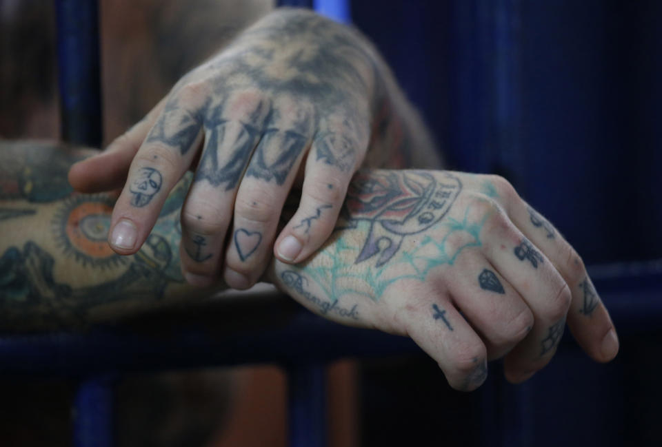 A detainee's tattooed-hands hand through the cell bars at the Bangkok immigration detention center in Bangkok, Thailand, Monday, Jan. 21, 2019. Advocates for the protection of refugees and asylum seekers lauded a commitment by Thailand on Monday to release children held in its immigration detention centers. (AP Photo/Sakchai Lalit)