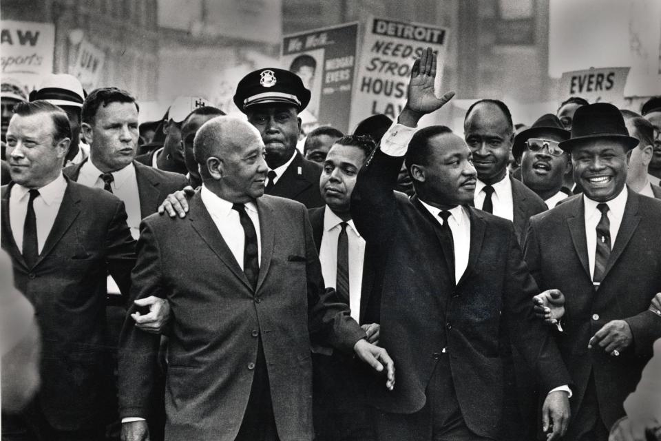 Martin Luther King Jr. waves to onlookers as he leads the 125,000 strong "Walk to Freedom" on Woodward Avenue in Detroit in 1963. From left to right in the front row are Walter Reuther, Benjamin McFall, Cmdr. George Harge (a cop with cap), King and the Rev. C.L. Franklin.