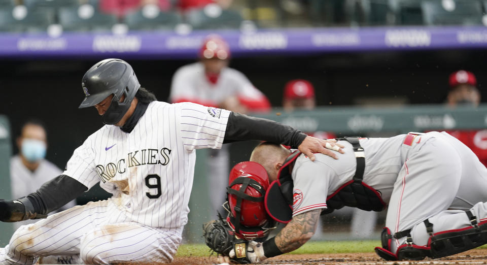 Cincinnati Reds catcher Tucker Barnhart, right, tags out Colorado Rockies' Connor Joe, who tried to score on a ground ball hit by Ryan McMahon during the first inning of a baseball game Thursday, May 13, 2021, in Denver. (AP Photo/David Zalubowski)