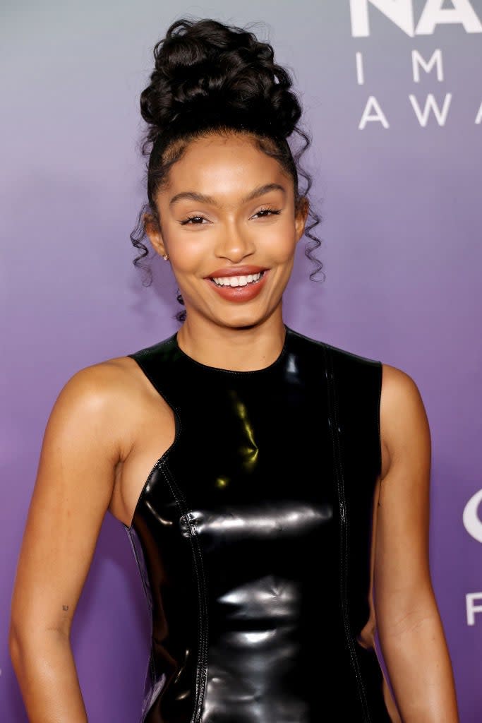 Woman in a sleek black sleeveless dress posing with a smile