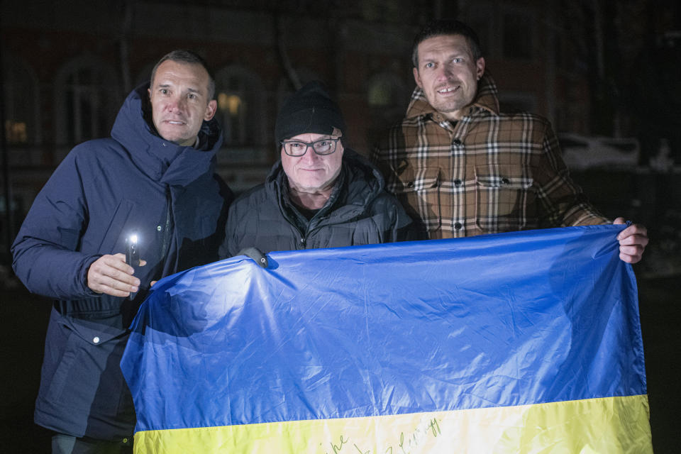 Ambassadors of UNITED24 fundraising platform former striker and coach of the Ukraine national soccer team Andriy Shevchenko, left, retired American astronaut Scott Kelly, centre, Ukrainian boxing heavyweight champion Oleksandr Usyk, right, pose with the Ukrainian flag in the city center in Kyiv, Ukraine, Monday, Nov. 28, 2022. Six ambassadors of UNITED24 fundraising platform, Andriy Shevchenko, Oleksandr Usyk, Scott Kelly among them, simultaneously announced a joint charity campaign have teamed up to raise funds for generators that will be used to power Ukrainian hospitals. (AP Photo/Andrew Kravchenko)