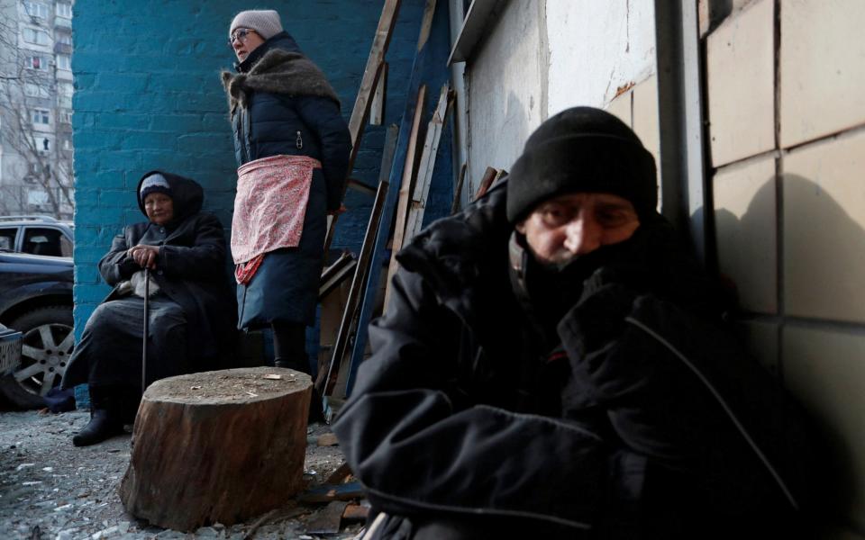 Locals take refuge outside an apartment building damaged in Mariupol - REUTERS/Alexander Ermochenko