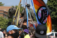 A protester holds a flag as crews lower the statue of Confederate General J.E.B. Stuart after removing it from its pedestal on Monument Avenue Tuesday, July 7, 2020, in Richmond, Va. The statue is one of several that will be removed by the city as part of the Black Lives Matter reaction. (AP Photo/Steve Helber)