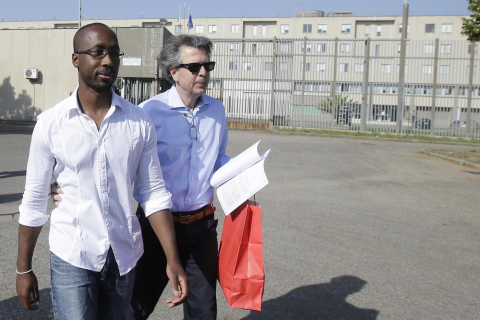 FILE - Rudy Guede, left, leaves the penitentiary for a temporary release of thirty-six hours, in Viterbo, Italy, on June 25, 2016. Guede, the only person convicted in the 2007 murder of British student Meredith Kercher has been freed after serving most of his 16-year prison sentence. Amanda Knox faces yet another trial for slander in a case that could remove the last remaining guilty verdict against her eight years after Italy's highest court definitively threw out her conviction for the murder of her 21-year-old British roommate, Meredith Kercher. (AP Photo/Gregorio Borgia, File)