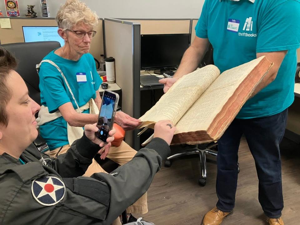 Thriftbooks director of vintage William Shelton displays a 16th century Rosetta Stone style book to a "Teal Ticket" winner and guest on Oct. 20, 2023.