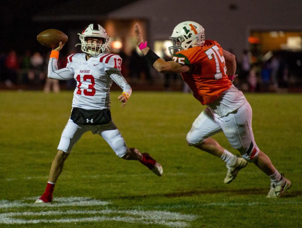 Holliston High School senior captain and quarterback TJ Kiley looks to throw with Hopkinton senior captain Justin Sokol in pursuit on Oct. 28, 2022.