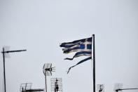 A frayed Greek national flag flutters among antennas atop a building in central Athens, Greece July 20, 2015.REUTERS/Alkis Konstantinidis