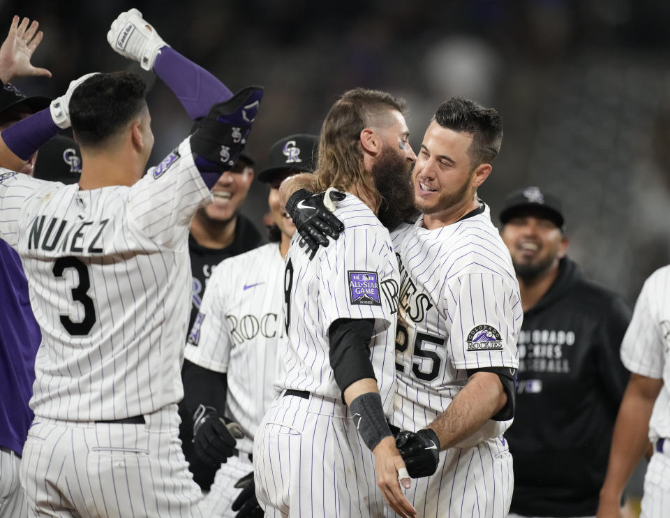 Colorado Rockies' C.J. Cron, right, is congratulated by Charlie Blackmon, center, and Dom Nunez after Cron drove in the winning run in the 10th inning of a baseball game against the Milwaukee Brewers on Friday, June 18, 2021, in Denver. The Rockies won 6-5. (AP Photo/David Zalubowski)