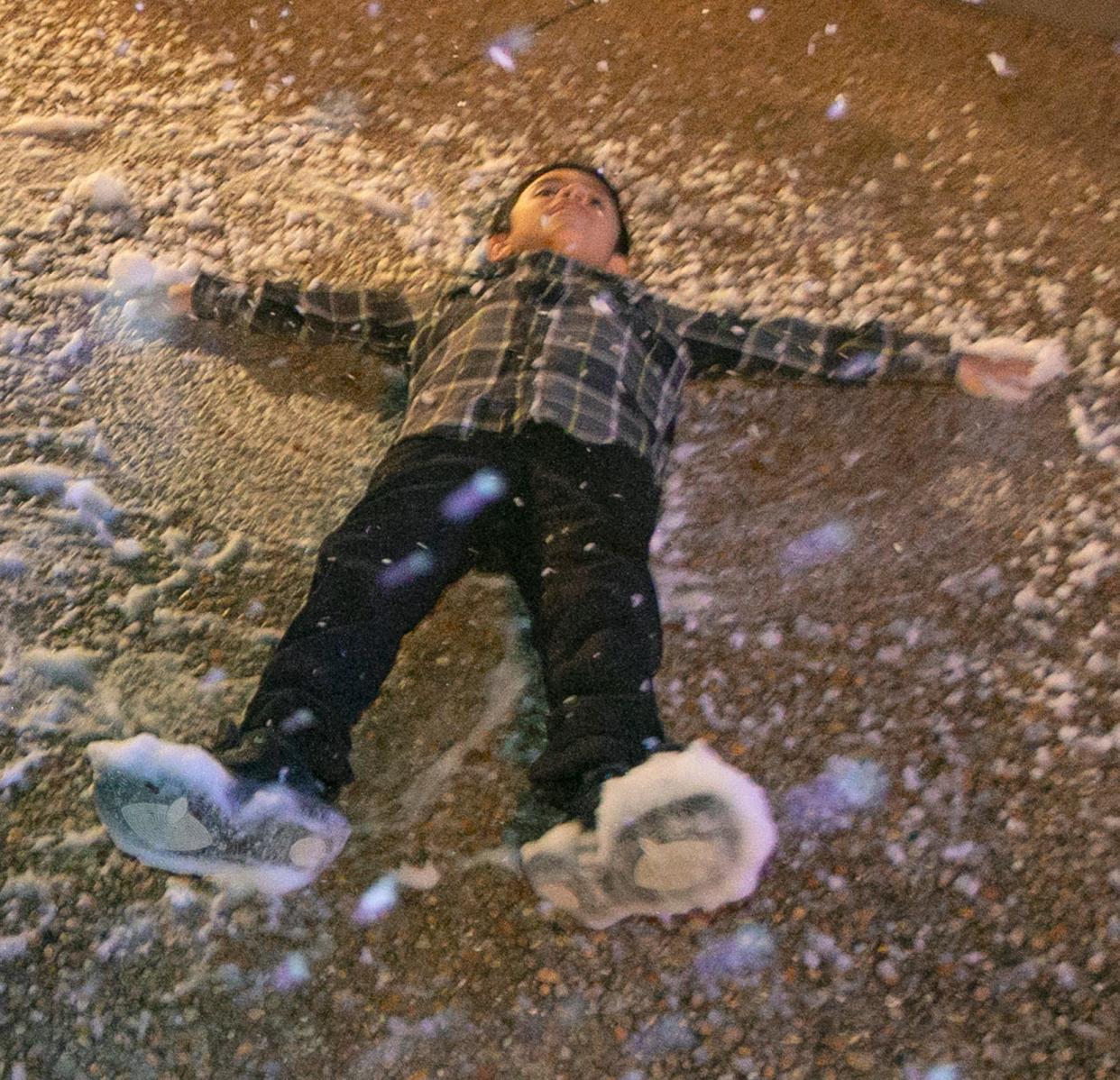 Bronson Barajas, 8, has fun as he makes a snow angel while playing in the artificial snow during the City of Lakeland's 40th Annual Snowfest at the Lake Mirror Promenade Friday night. December 4, 2020.