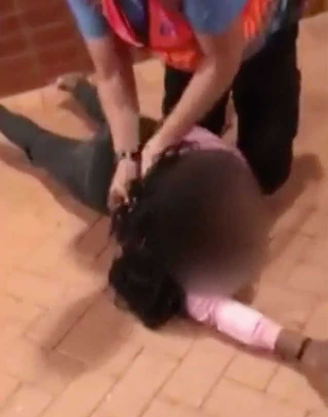 One of the girls is seen handcuffed and restrained. Source: 7 News