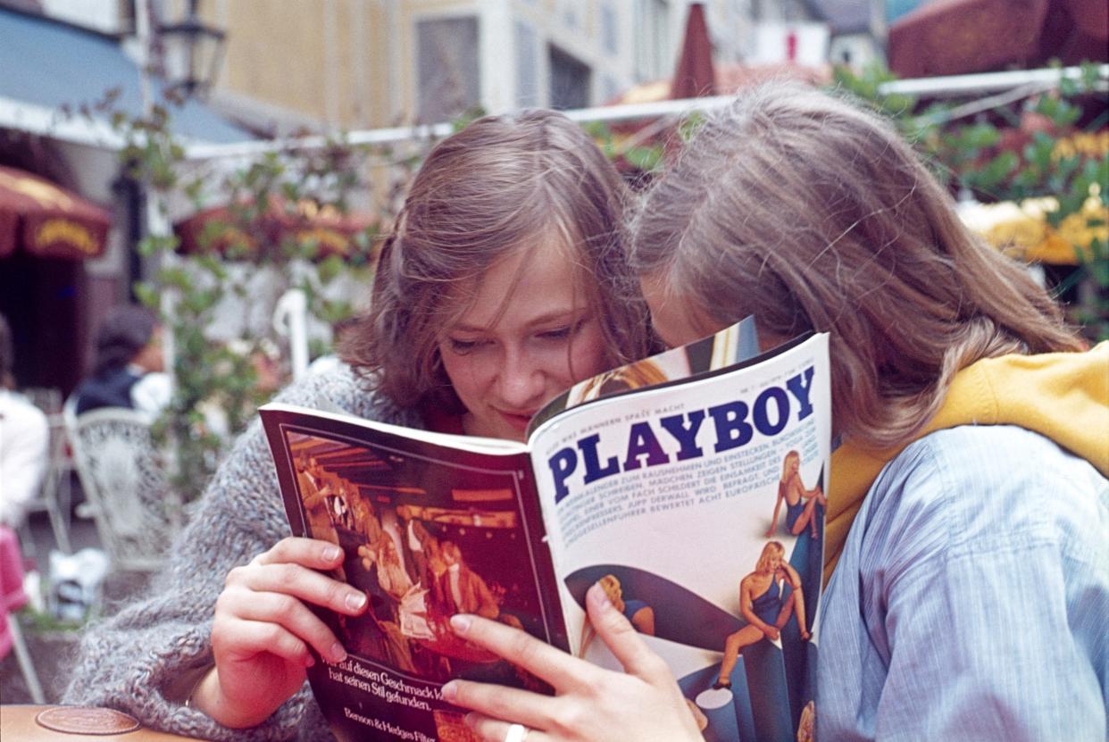 Hamelin, Lower Saxony, 1979. Two young women read together an article in a well-known men's magazine in a pedestrian area.