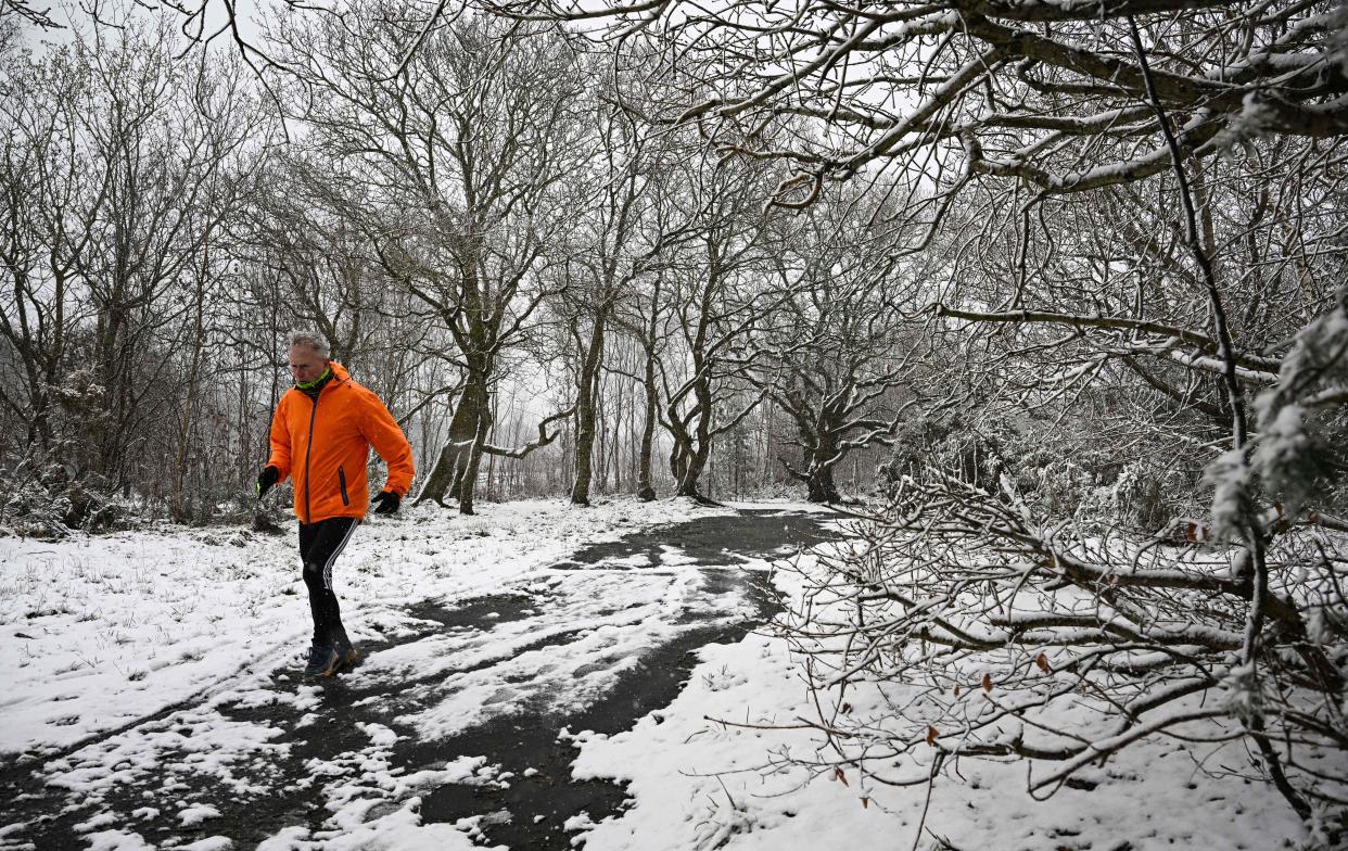 A runner braves the snow on Bidston Hill, near Birkenhead, in north west England on March 9, 2023 (AFP via Getty Images)