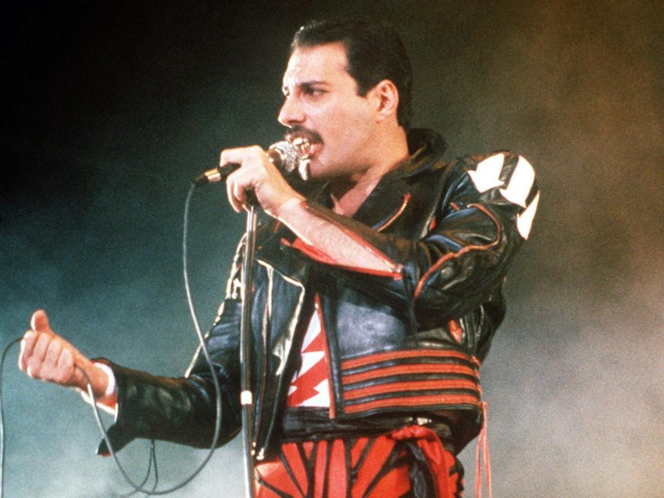 freddie mercury singing on stage with a mic