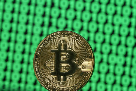 A token of the virtual currency Bitcoin is seen placed on a monitor that displays binary digits in this illustration picture, December 8, 2017. REUTERS/Dado Ruvic/Illustration