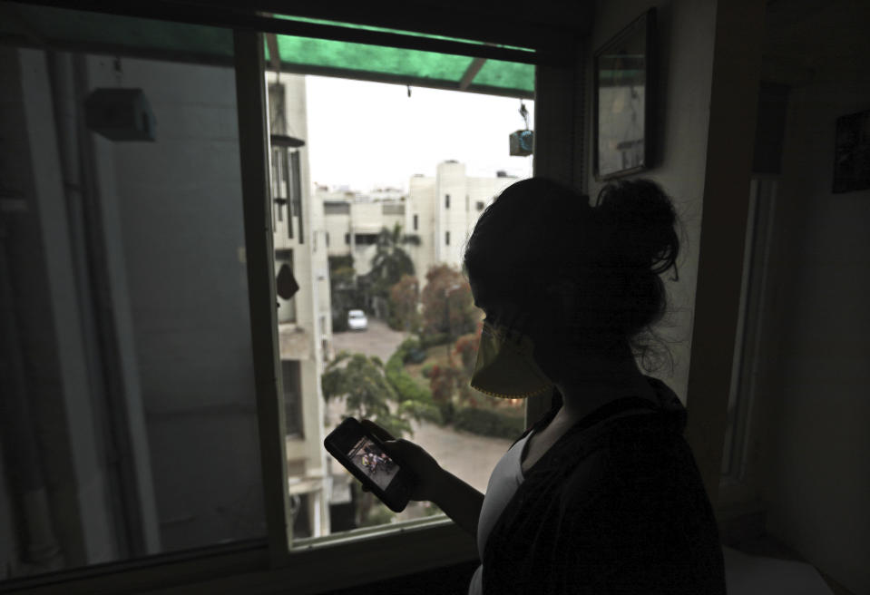 In this Tuesday, March 24, 2020 photo, an Indian girl wearing a face mask as a precaution from coronavirus watches a video on the WhatsApp app in New Delhi, India. With the pandemic starting to gain a foothold in the region, social media are rife with bogus remedies, tales of magic cures and potentially hazardous medical advice. Experts are urging caution and say the “coronavirus infodemic” could have disastrous consequences. (AP Photo/Manish Swarup)