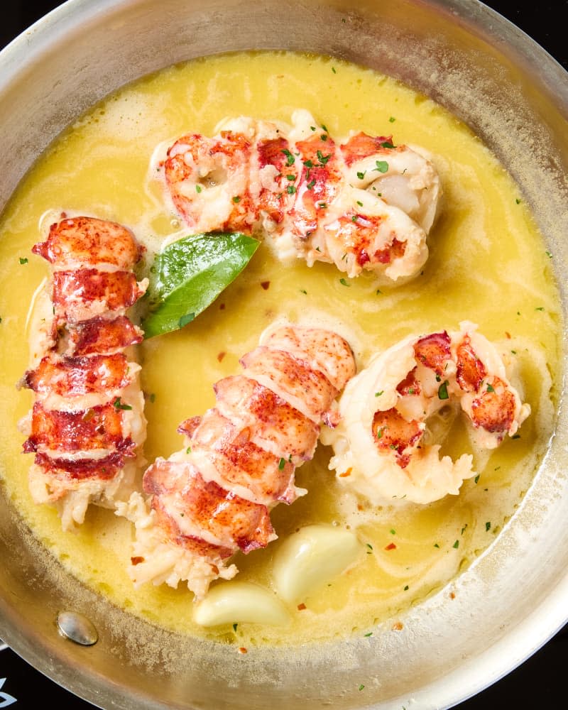 overhead shot of butter poached lobster tails in a pan.