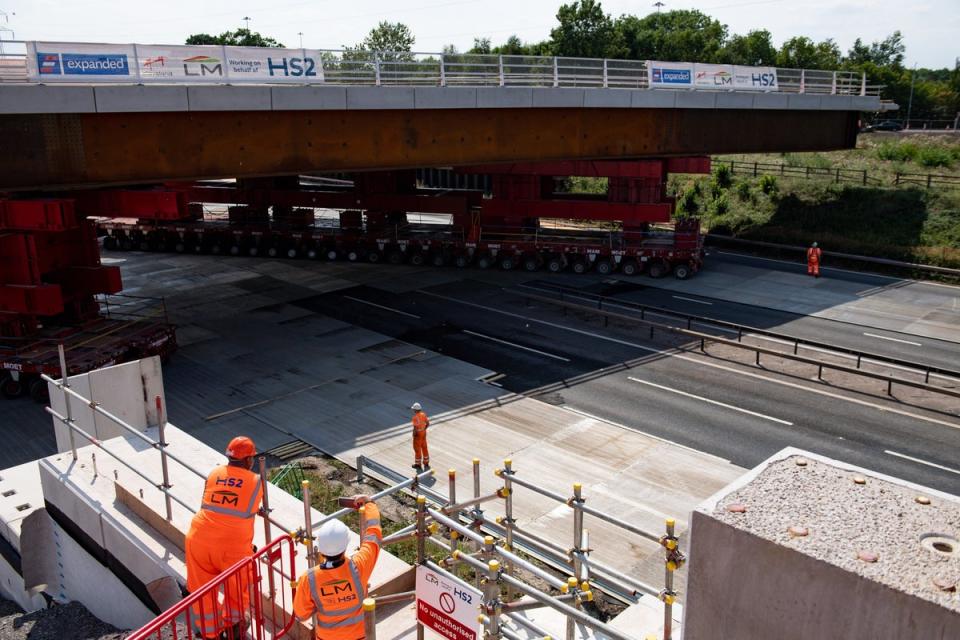 HS2 workers watch as a bridge is wheeled into position over the M42 at the HS2 interchange station site near Solihull (Jacob King/PA) (PA Archive)