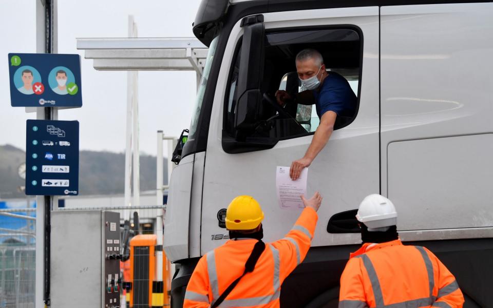 A lorry driver shows documentation to officials for both customs clearance and coronavirus disease test results as he arrives at the Eurotunnel on route to France on New Year's Day - Toby Melville/Reuters