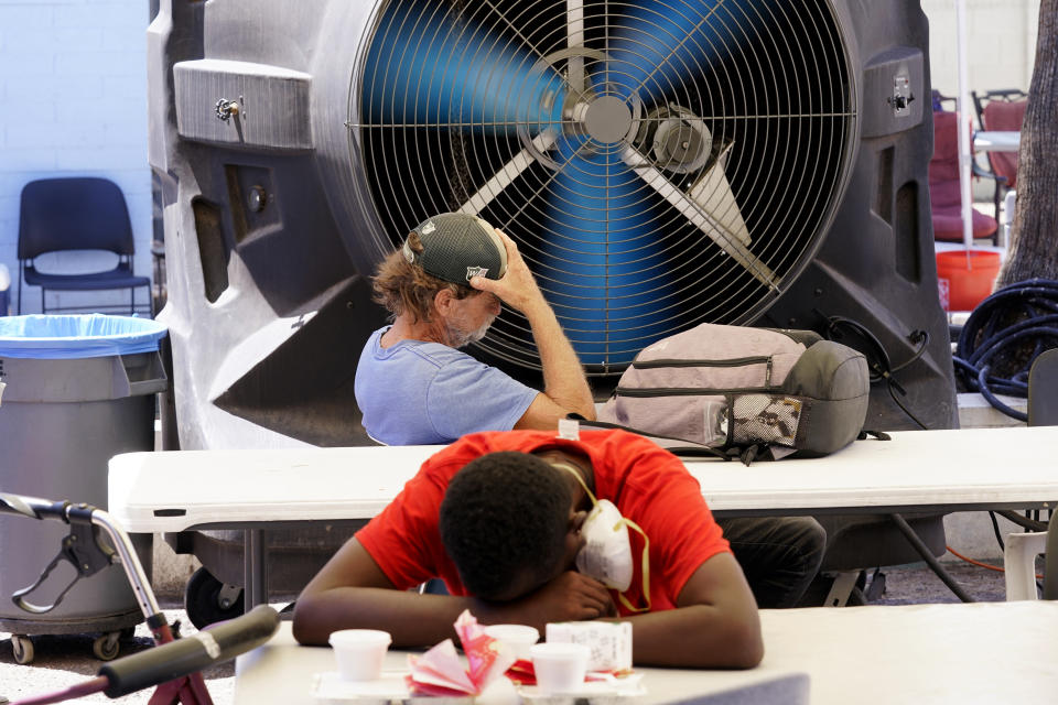 FILE - People try to keep cool at the Justa Center, a resource center catering to the older homeless population, as temperatures hit 110-degrees, July 19, 2022, in Phoenix. Thousands of homeless people who died this year and are being remembered at winter solstice events for Homeless Persons' Memorial Day. (AP Photo/Ross D. Franklin, File)