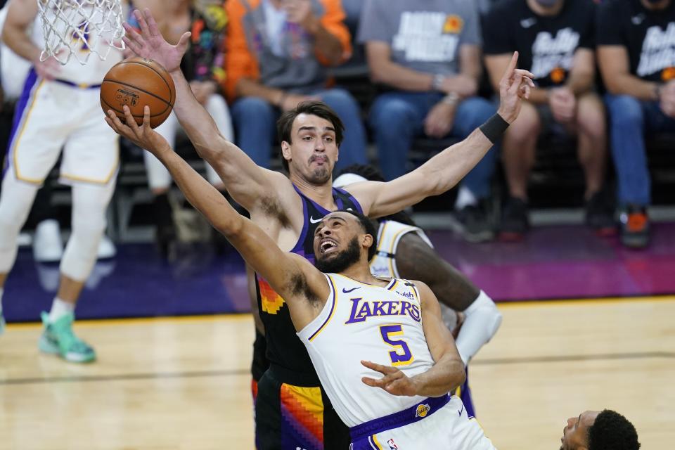 Los Angeles Lakers guard Talen Horton-Tucker (5) drives past Phoenix Suns forward Dario Saric to score during the first half of Game 1 of their NBA basketball first-round playoff series Sunday, May 23, 2021, in Phoenix. (AP Photo/Ross D. Franklin)