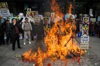 Anti-North Korean activists burn placards showing N.Korean leader Kim Jong-Un as they protest the latest nuclear test and rocket launch by Pyongyang, in Seoul, on February 11, 2016