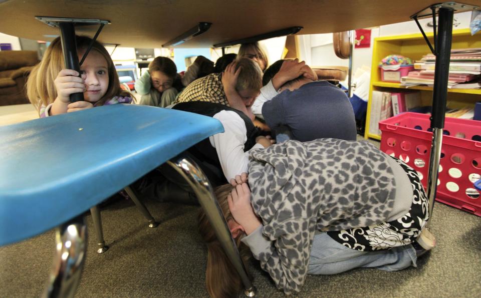 Jaely John, 7, left, a student at Twin Lakes Elementary School in Federal Way, Wash., takes shelter under a table with other students as they take part in an earthquake drill, Thursday, Oct. 18, 2012. Millions of people took part in the “Great Shakeout” earthquake drill across the country and elsewhere Thursday to practice and prepare for the possibility of real quakes in the future. (AP Photo/Ted S. Warren)
