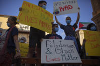 Protesters hold signs during a demonstration against the Israeli police after border police officers shot and killed Iyad al-Halak, an unarmed autistic Palestinian man, in the mixed Arab Jewish city of Jaffa, near Tel Aviv, Israel, after saying they suspected he was carrying a weapon, Sunday, May 31, 2020. Protesters gathered to protest the killing of al-Halak in Jerusalem and the killing of George Floyd in Minneapolis last week. (AP Photo/Oded Balilty)