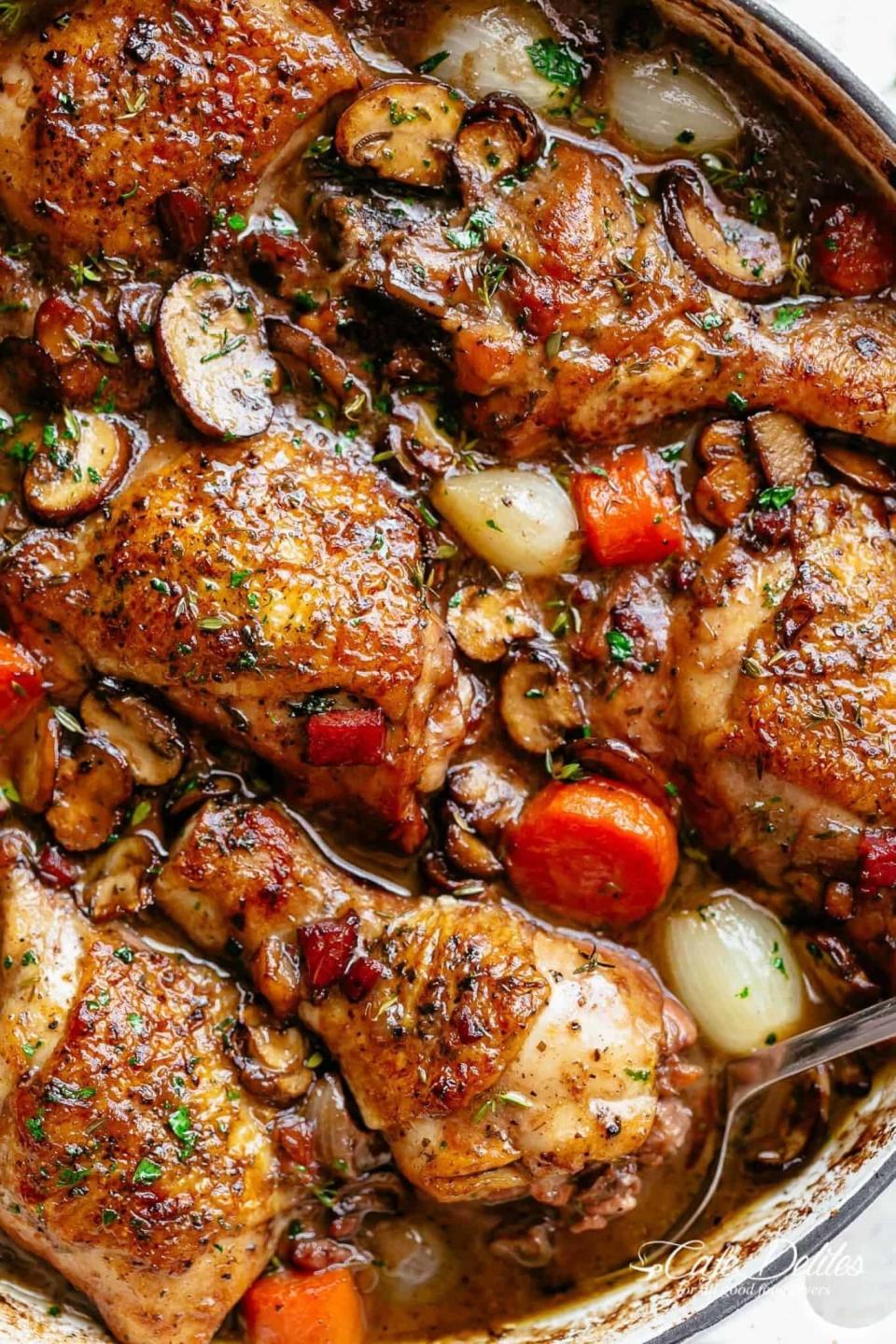 A pot of coq au vin with carrots and mushrooms