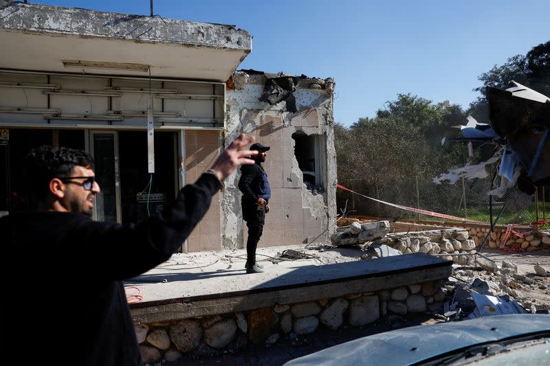 People stand next to a damaged building that was hit by a rocket launched from the Gaza Strip, in Netivot