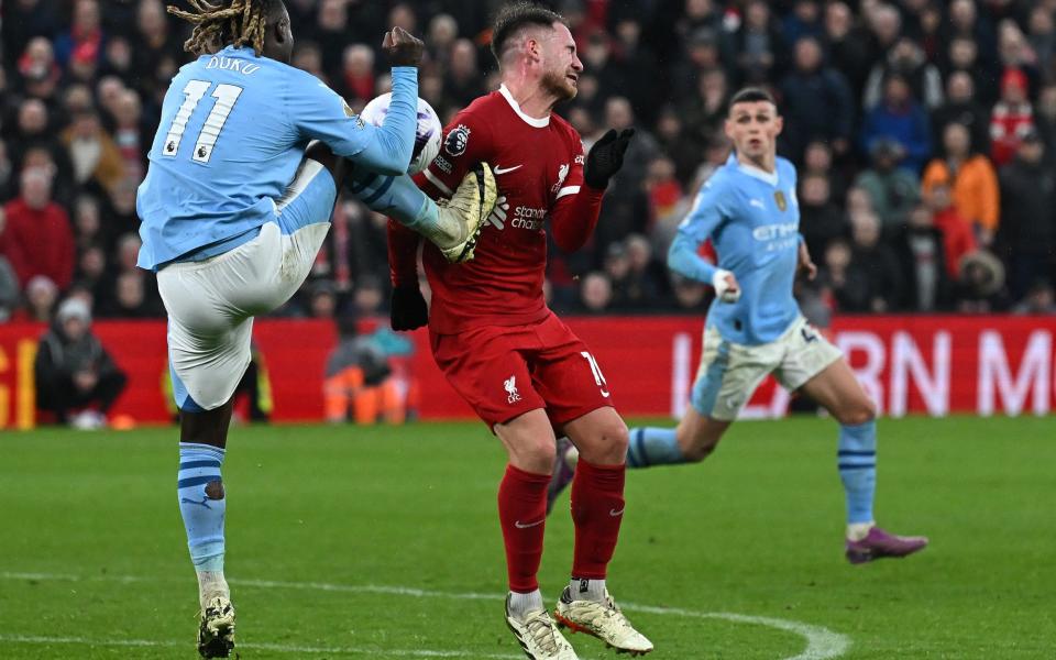 Manchester City's Belgian midfielder #11 Jeremy Doku (L) kicks Liverpool's Argentinian midfielder #10 Alexis Mac Allister