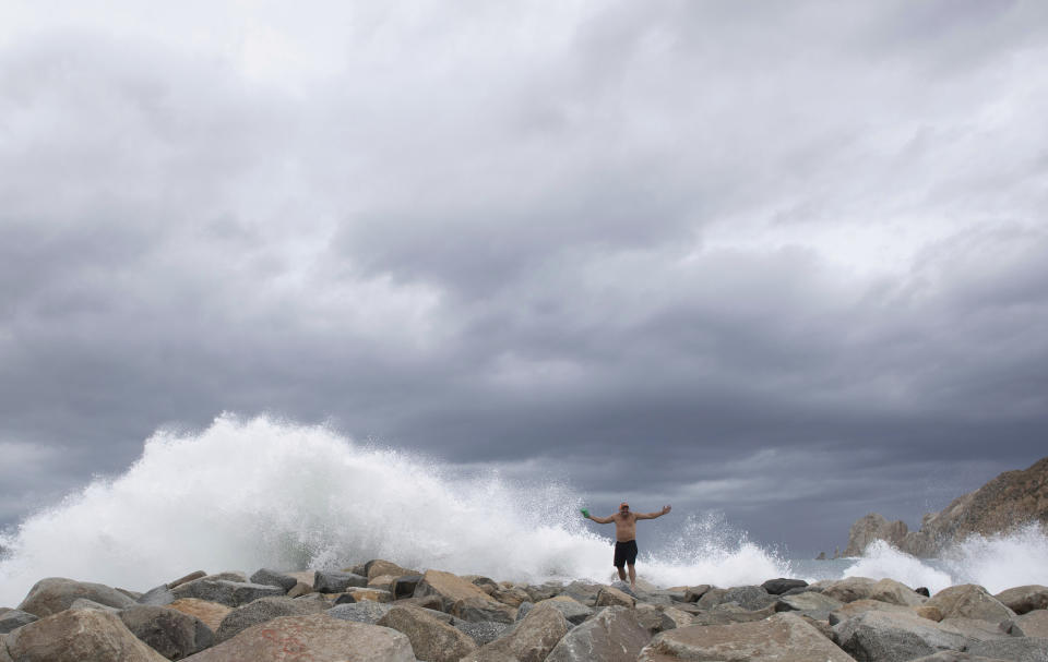 A tourist poses for a photo in front breaking waves before the expected arrival of Hurricane Lorena, in Los Cabos, Mexico, Friday, Sept. 20, 2019. Hurricane Lorena neared Mexico's resort-studded Los Cabos area Friday as owners pulled their boats from the water, tourists hunkered down in hotels, and police and soldiers went through low-lying, low-income neighborhoods urging people to evacuate. (AP Photo/Fernando Castillo)