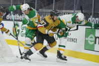 Minnesota Wild center Nico Sturm (7), Vegas Golden Knights defenseman Shea Theodore (27) and left wing Kirill Kaprizov (97) battle for the puck during the first period of an NHL hockey game Wednesday, March 3, 2021, in Las Vegas. (AP Photo/John Locher)