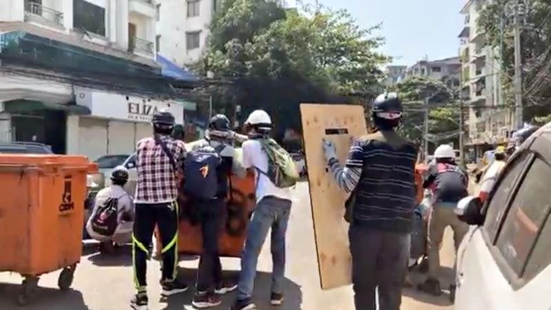 Protesters hide behind barricades during an anti-coup protest in Yangon, Myanmar