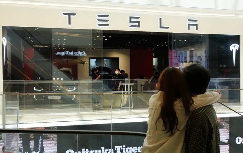 A couple looks at a Tesla dealership in Hanam