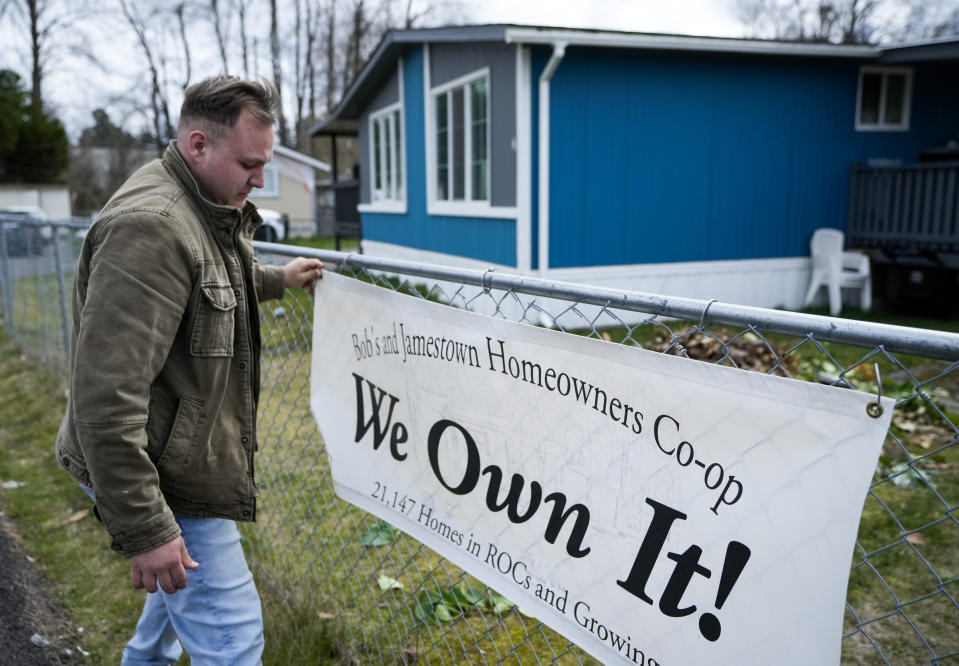 Gadiel Galvez, 22, adjusts a sign stating that his resident cooperative owns their mobile home park, Bob’s and Jamestown Homeowners Cooperative, in Lakewood, Wash., on Saturday, March 25, 2023. When residents learned the park’s owner was looking to sell, they formed a cooperative and bought it themselves amid worries it would be redeveloped. Since becoming owners in September 2022, residents have worked together to manage and maintain the park. (AP Photo/Lindsey Wasson)