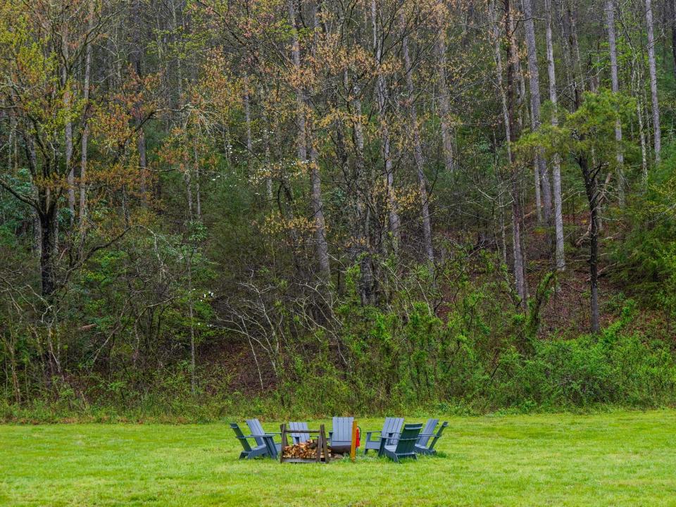 A circle of green chairs on green grass with a forest in the background