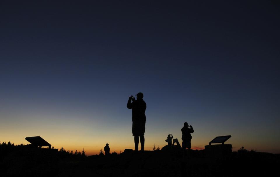 FILE - Tourists photograph the sunset at the summit of Cadillac Mountain in Acadia National Park, Oct. 2, 2014, near Bar Harbor, Maine. The nearby Jordan Pond Shore Trail offers stunning views and a way to get your steps in while enjoying the foliage. A proposal before the Maine Legislature would ask voters to approve $30 million in public money for the design, development and maintenance of both motorized and non-motorized trails. (AP Photo/Robert F. Bukaty, File)