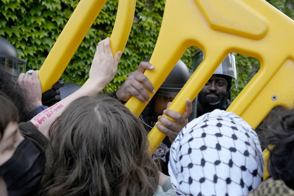 Pro-Palestinian protesters push back as University of Chicago police officers reposition a barricade keeping protesters from the university's quad while the student encampment is dismantled Tuesday, May 7, 2024, in Chicago. (AP Photo/Charles Rex Arbogast)