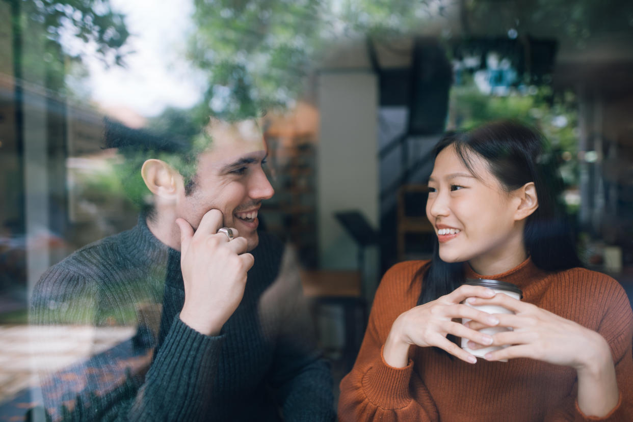 Couple having coffee on a date talking and smile together.