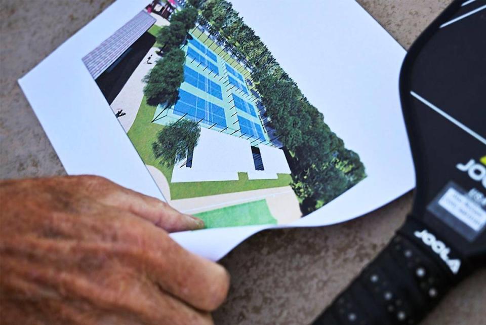 Alan McCuen, a member of the Fresno Area Pickleball group, shows a plan for permanent pickleball courts in Fresno as pickleball enthusiasts play at Rotary East Park Wednesday morning, June 21, 2023 in Fresno.