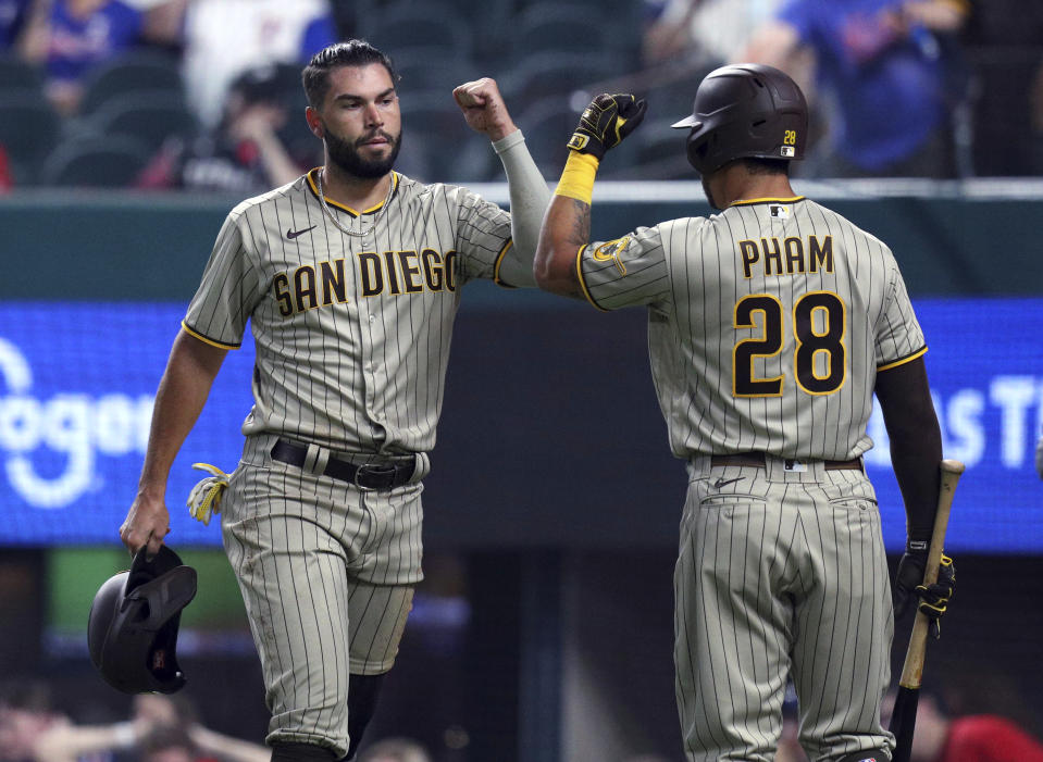 San Diego Padres Eric Hosmer (30) fist-bumps Tommy Pham (28) after scoring against the Texas Rangers during the first inning of a baseball game Friday, April 9, 2021, in Arlington, Texas. (AP Photo/Richard W. Rodriguez)