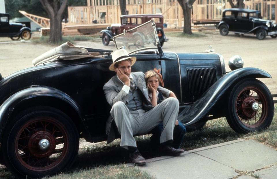 ryan o'neal and tatum o'neal in 'paper moon' sit against a car with their heads resting in their palms