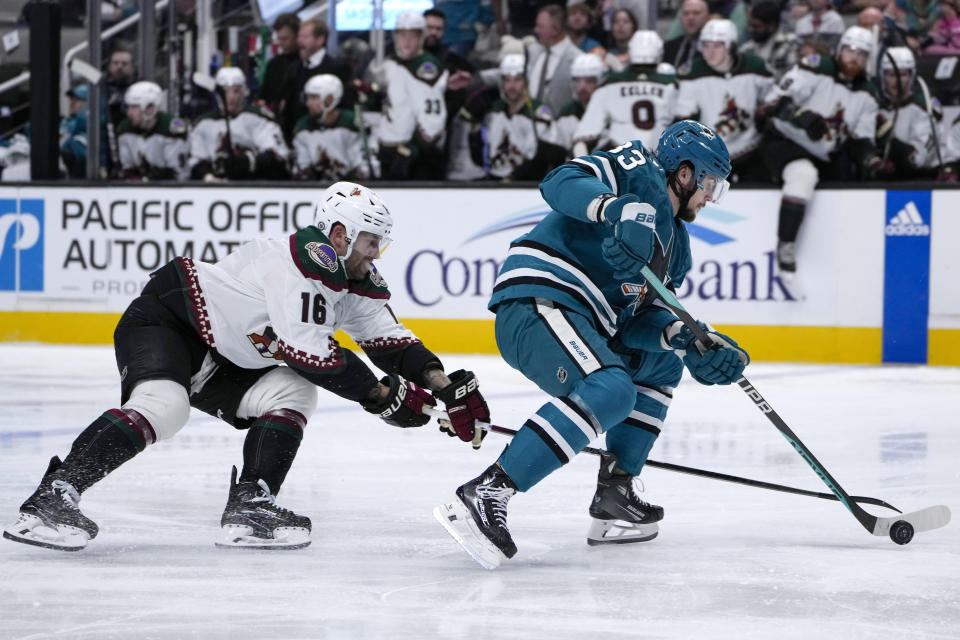 San Jose Sharks defenseman Calen Addison, right, moves the puck while defended by Arizona Coyotes left wing Jason Zucker during the second period of an NHL hockey game Thursday, Dec. 21, 2023, in San Jose, Calif. (AP Photo/Godofredo A. Vásquez)