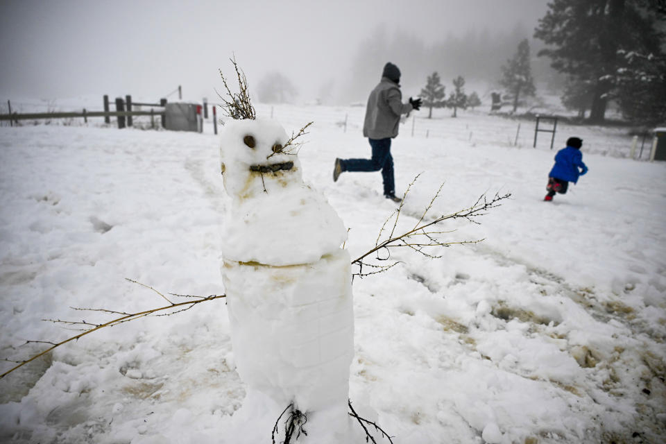 People play in the snow near a snowman in the Cleveland National Forest Wednesday, Feb. 7, 2024, in eastern San Diego County, Calif. According to the National Weather Service snow level is down to 4500 feet in the San Diego County mountains. (AP Photo/Denis Poroy)
