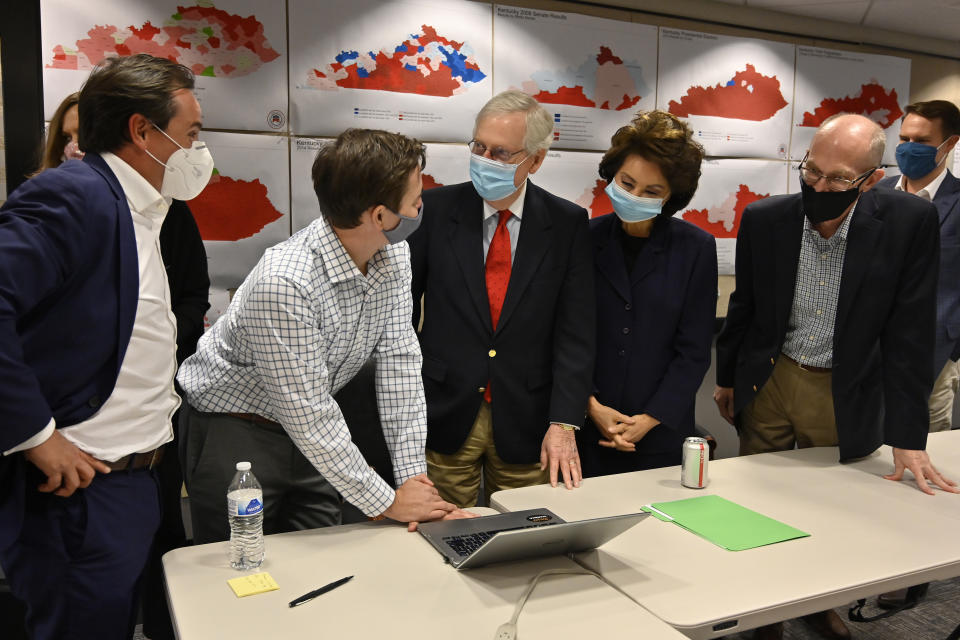 Republican Senate candidate Sen. Mitch McConnell, center, talks with a staff member as they gather around to watch the results of his reelection campaign in Louisville, Ky., Tuesday, Nov. 3, 2020. McConnell's wife, Elaine Chao, stands next to him. (AP Photo/Timothy D. Easley)